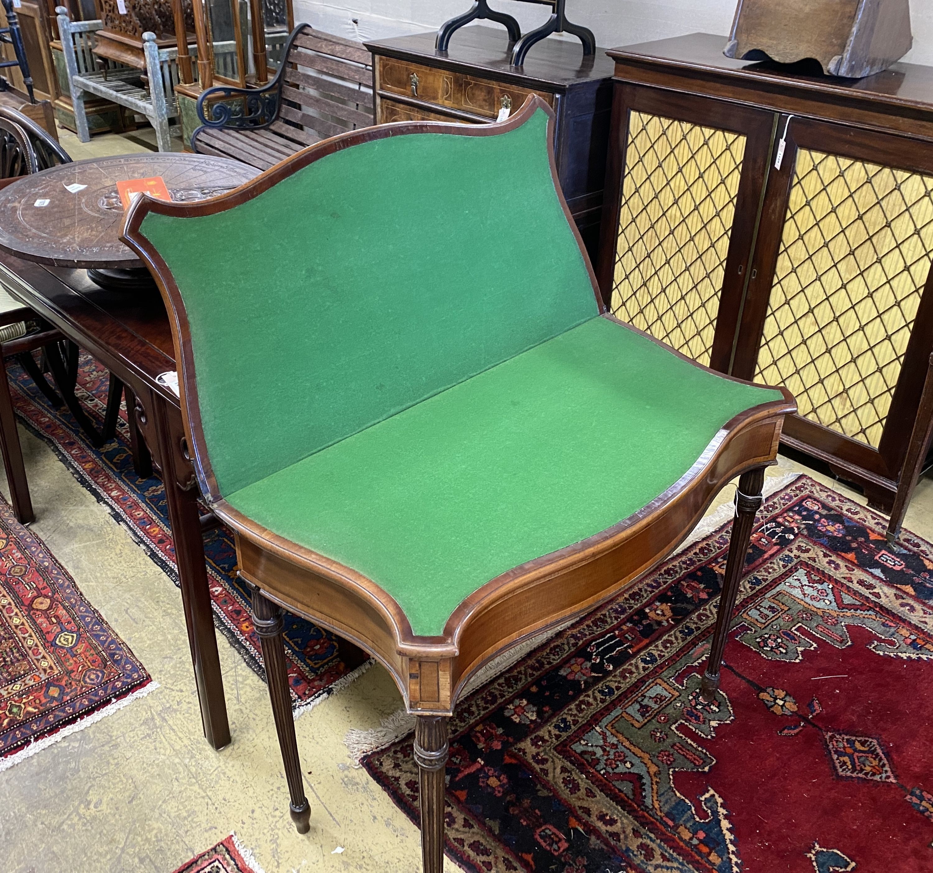 A George III serpentine fronted banded mahogany folding card table, width 88cm, depth 44cm, height 74cm